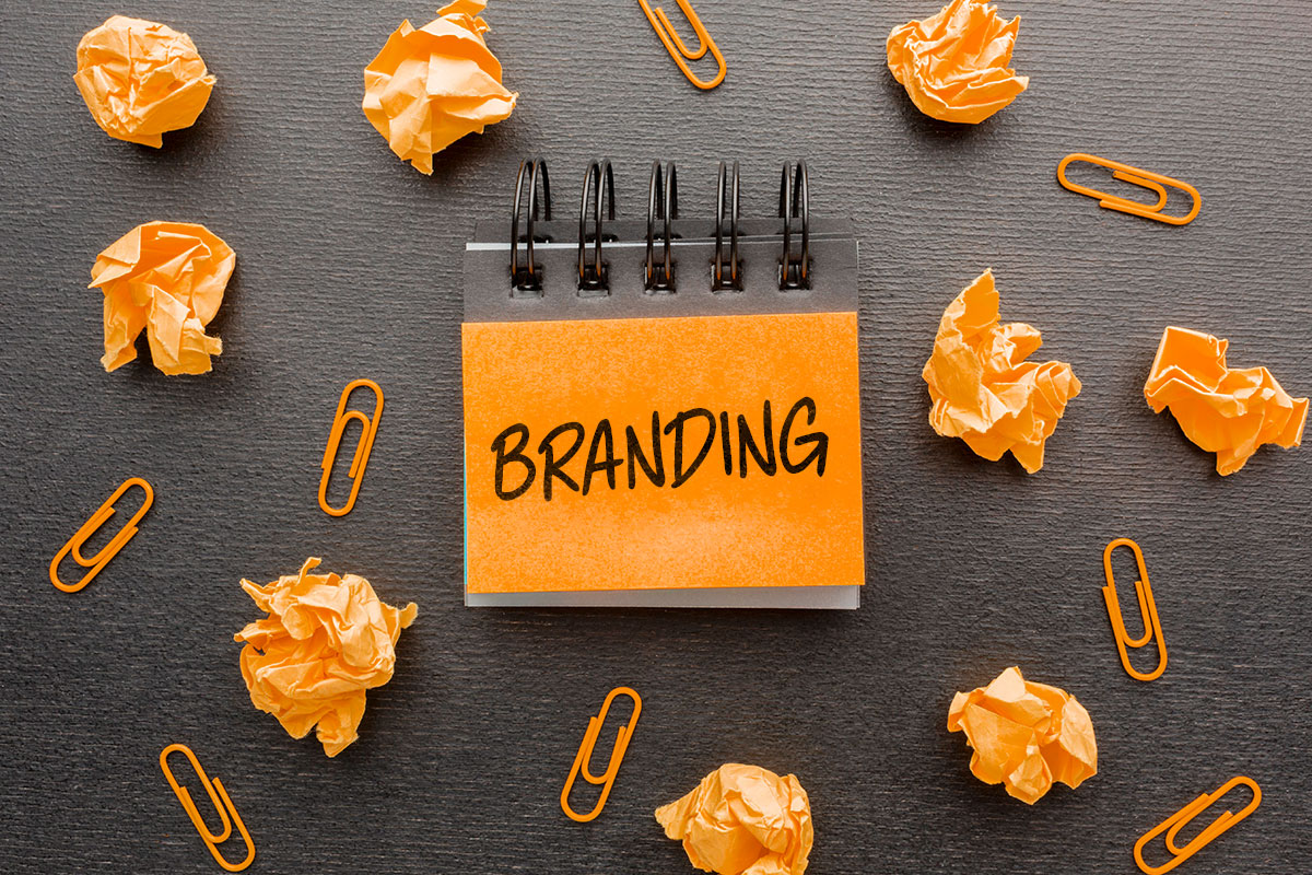 The word "branding" written on a post-it note surrounded by crumpled notes and paperclips