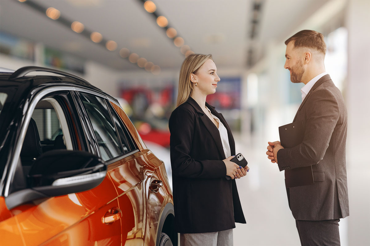 Car dealership employee speaking to a customer next to an SUV