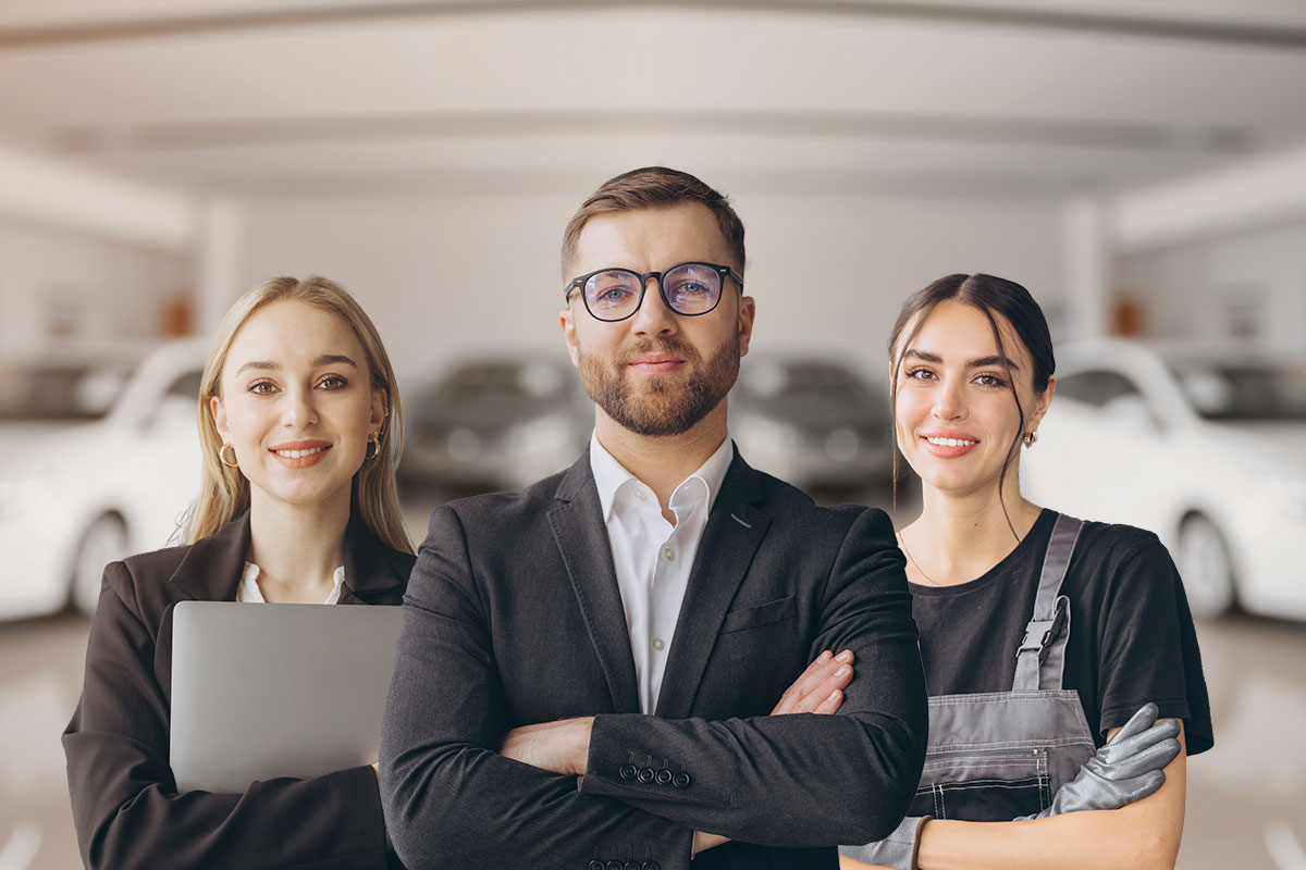 Three rental car business employees posing in front of a garage