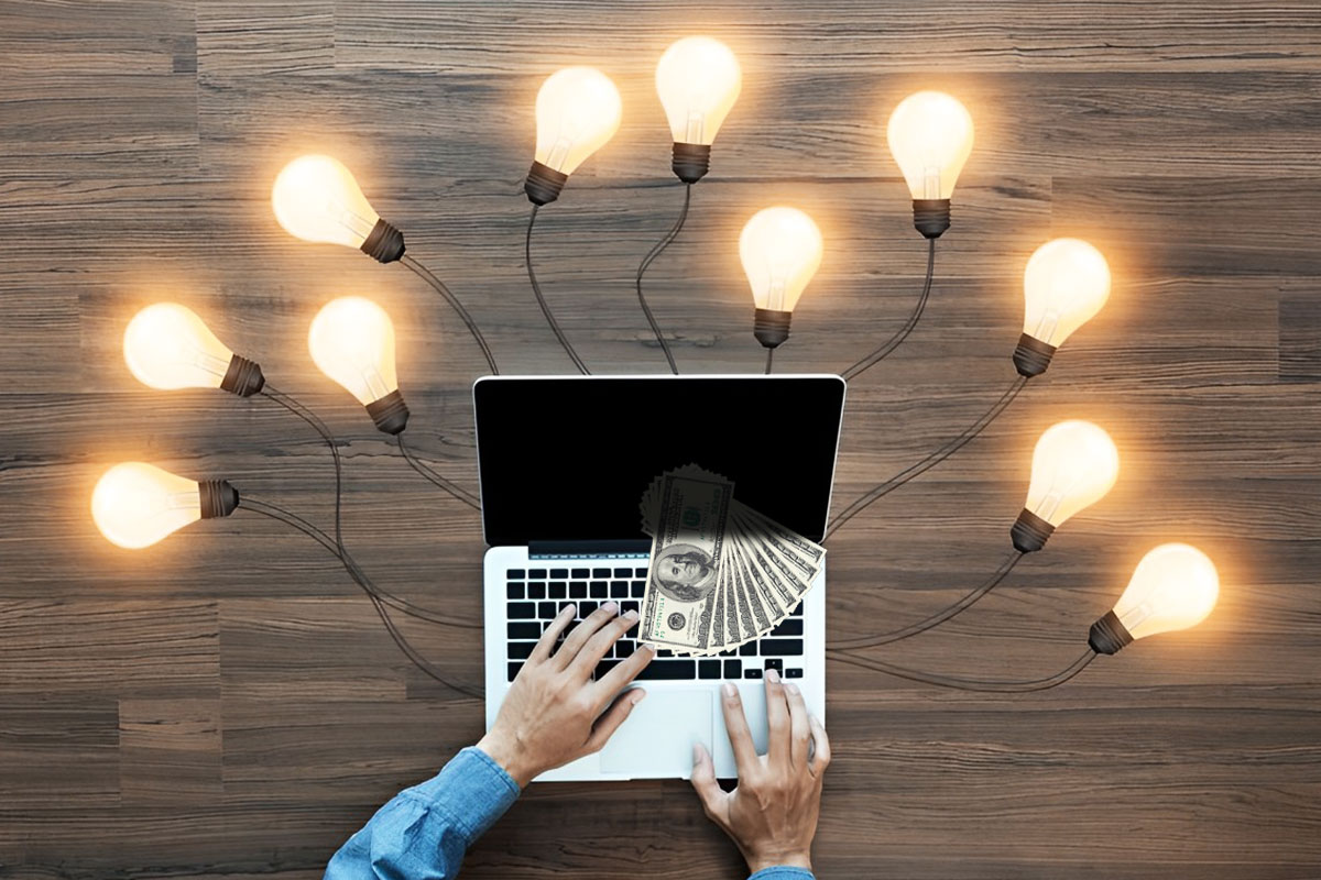 How to Make $1000 a Day 4 Lightbulbs lit up around a laptop covered in cash