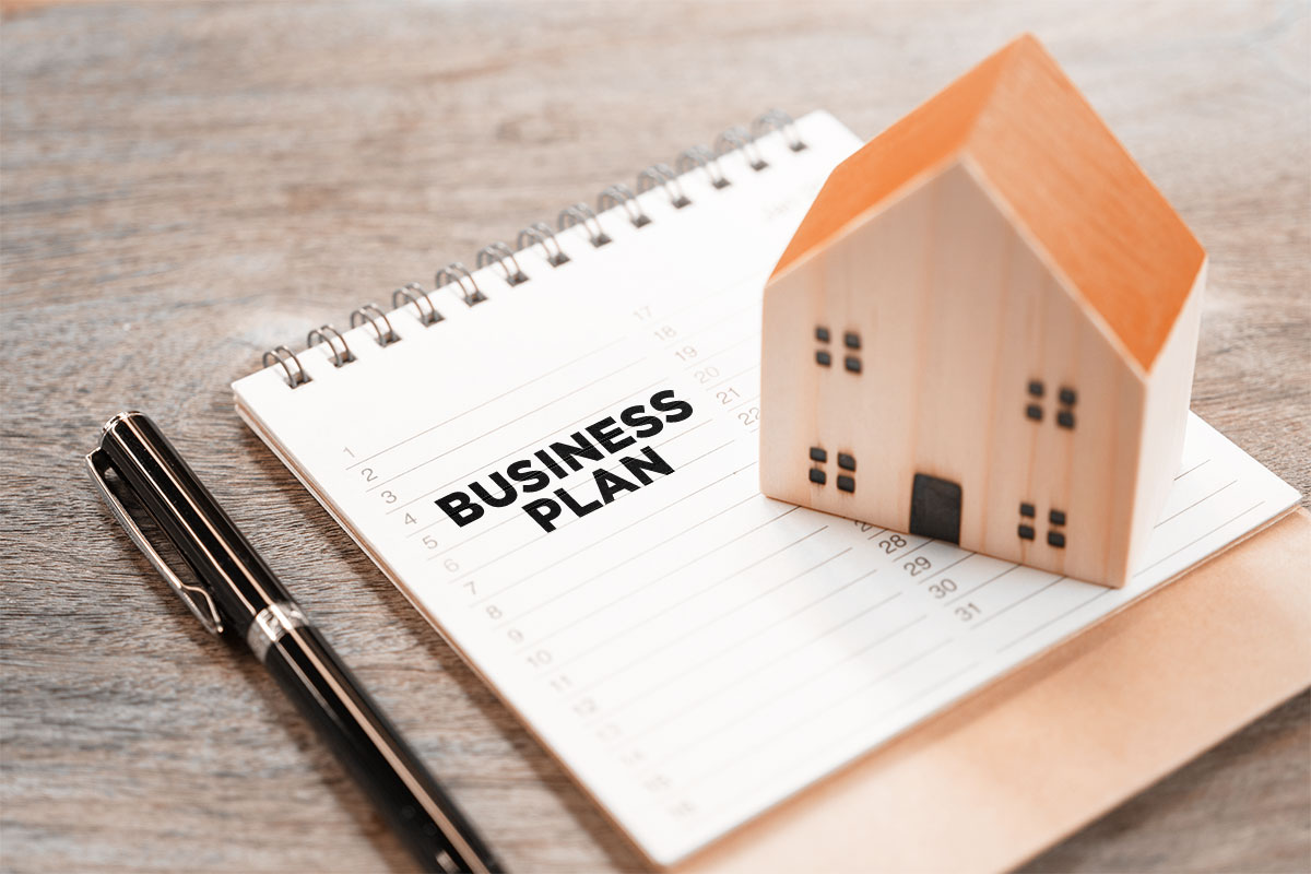 Miniature wooden model of a house on top of a business plan