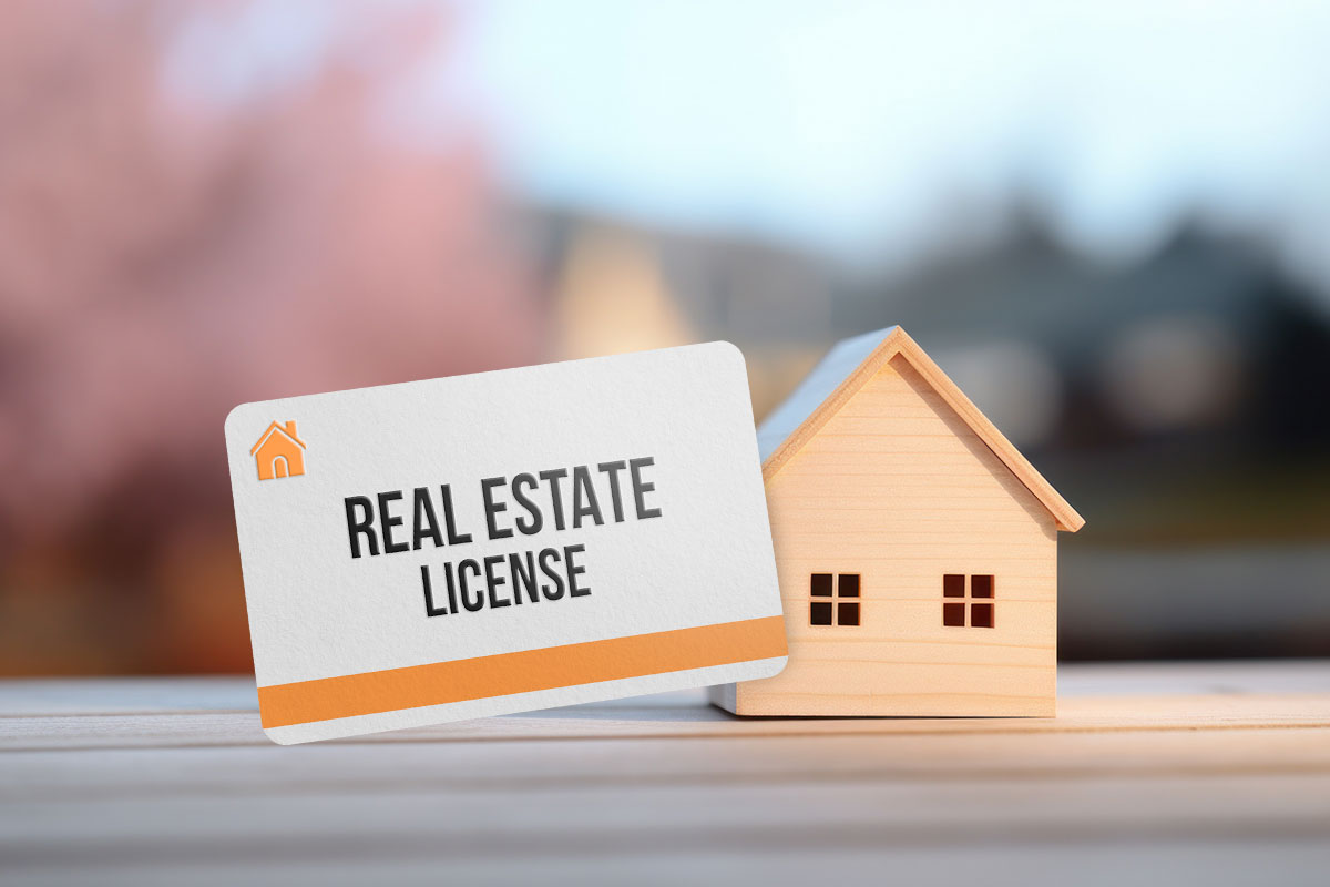 Real estate license card sitting on a table next to a miniature wooden house