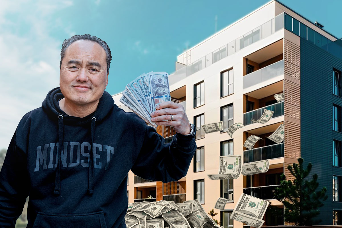 Owner of Thach Real Estate holding cash while standing in front of an apartment building