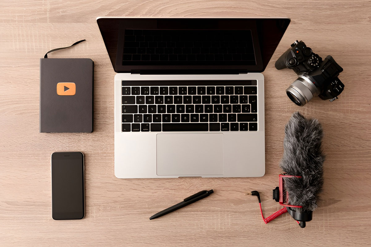 How to Start a $45K/Month YouTube Channel 8 A laptop, a camera, a phone, and other YouTube channel supplies sitting on a desk