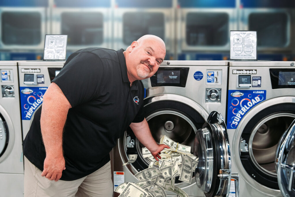 Dave Menz, owner of Queen City Laundry, reaching into a washing machine full of cash