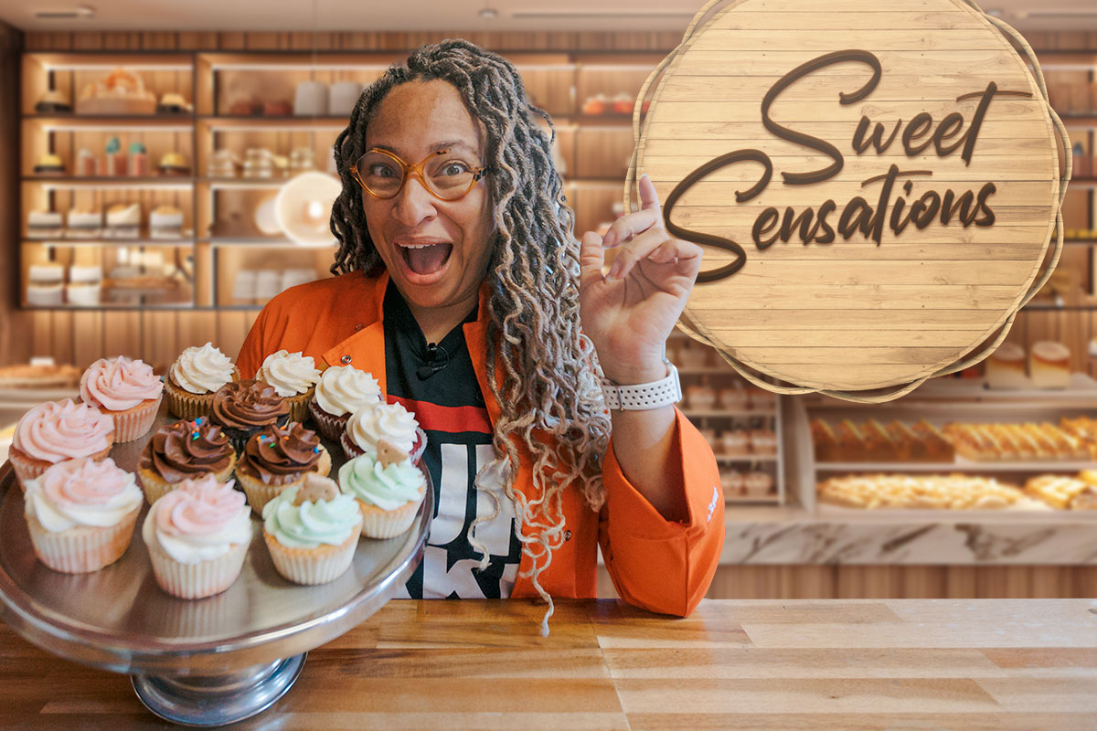 Bakery owner posing with a tray of cupcakes next to a sign that says "Sweet Sensations"