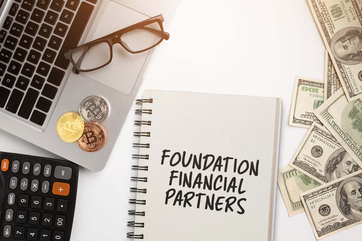 425 Consulting Business Names 2 A notebook with the name Foundation Financial Partners on a desk next to a laptop, cash, and a calculator.