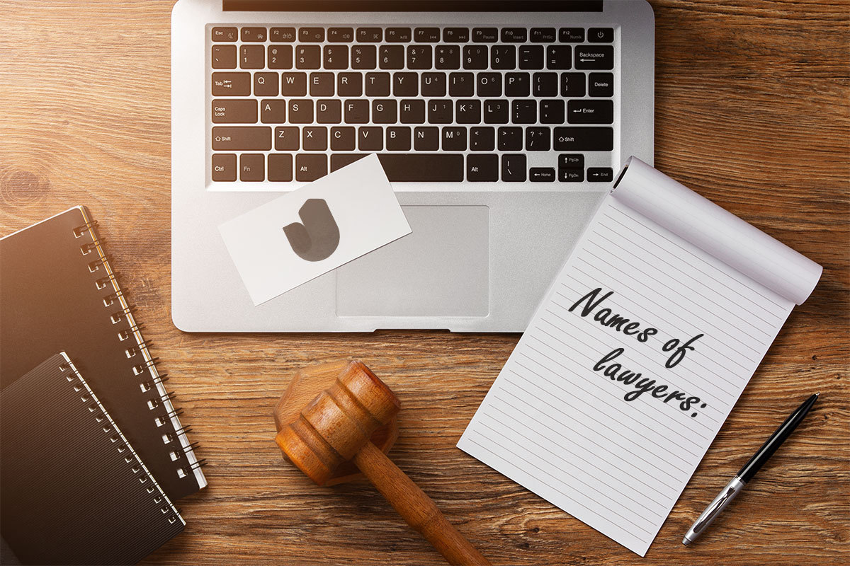 337 Law Firm Names 7 A notebook with names of lawyers written on the front next to a gavel, a pen, and a laptop.