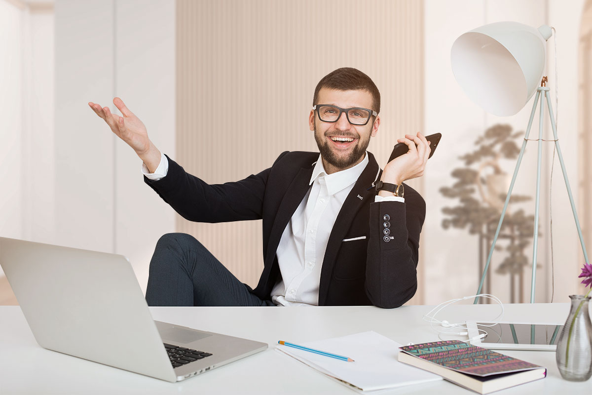 How to Start a $1.5M/Year Business From Home (in 9 Steps) 12 A happy business owner working at home behind a minimalist desk while holding a cell phone.