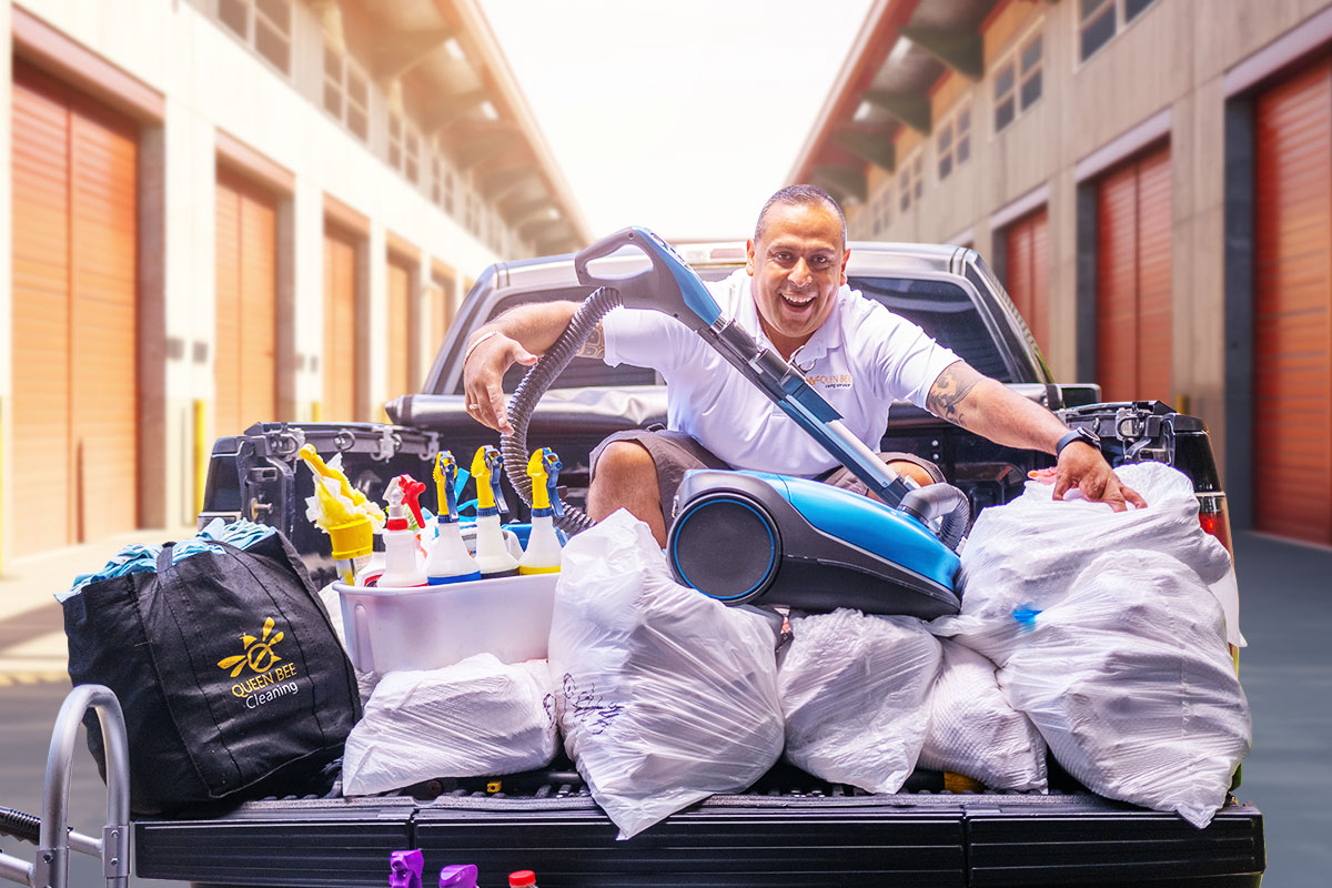 Chris Mondragon sitting in the bed of a truck with cleaning supplies and trash bags.