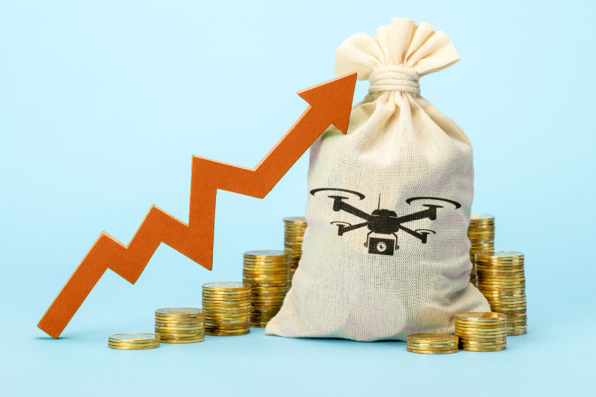 A bag full of money with a drone logo on the front next to piles of gold coins and an arrow showing upward growth.