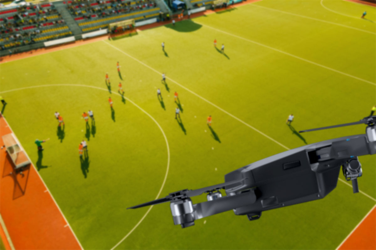 A drone flying over a soccer field while people play below.