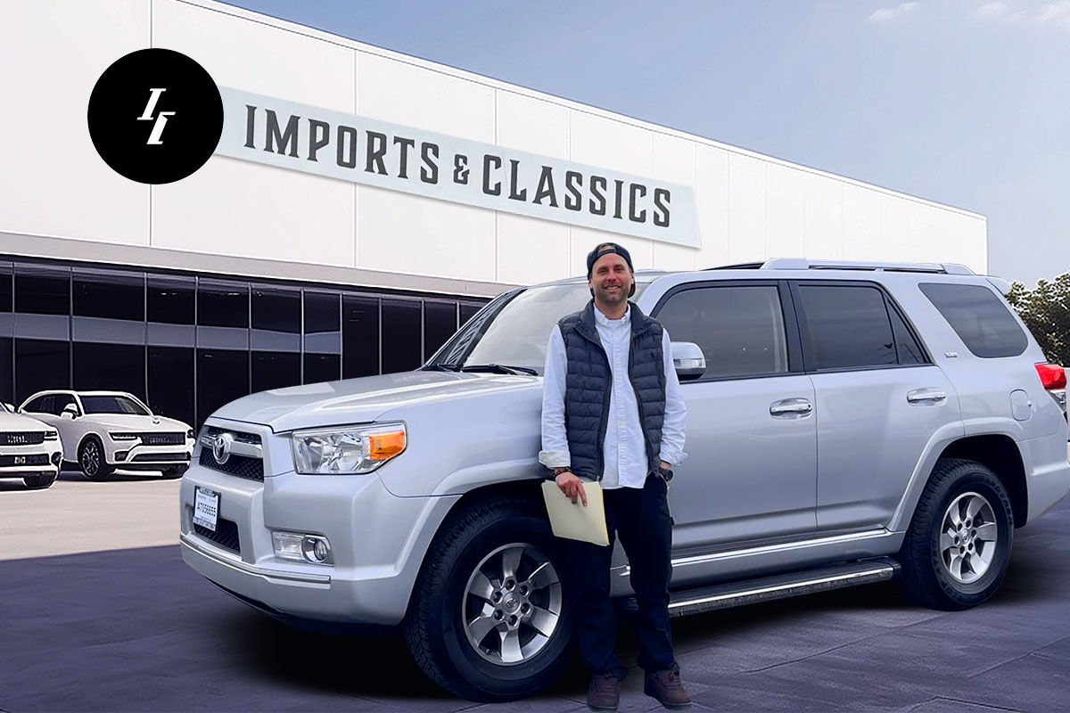 How to Start a Used Car Dealership 16 Dealership owner Carlos Becerra standing in front of an SUV and the building for Imports & Classics.
