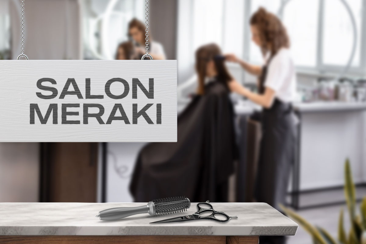 A salon employee cutting a customer's hair next to a sign that says Salon Meraki.