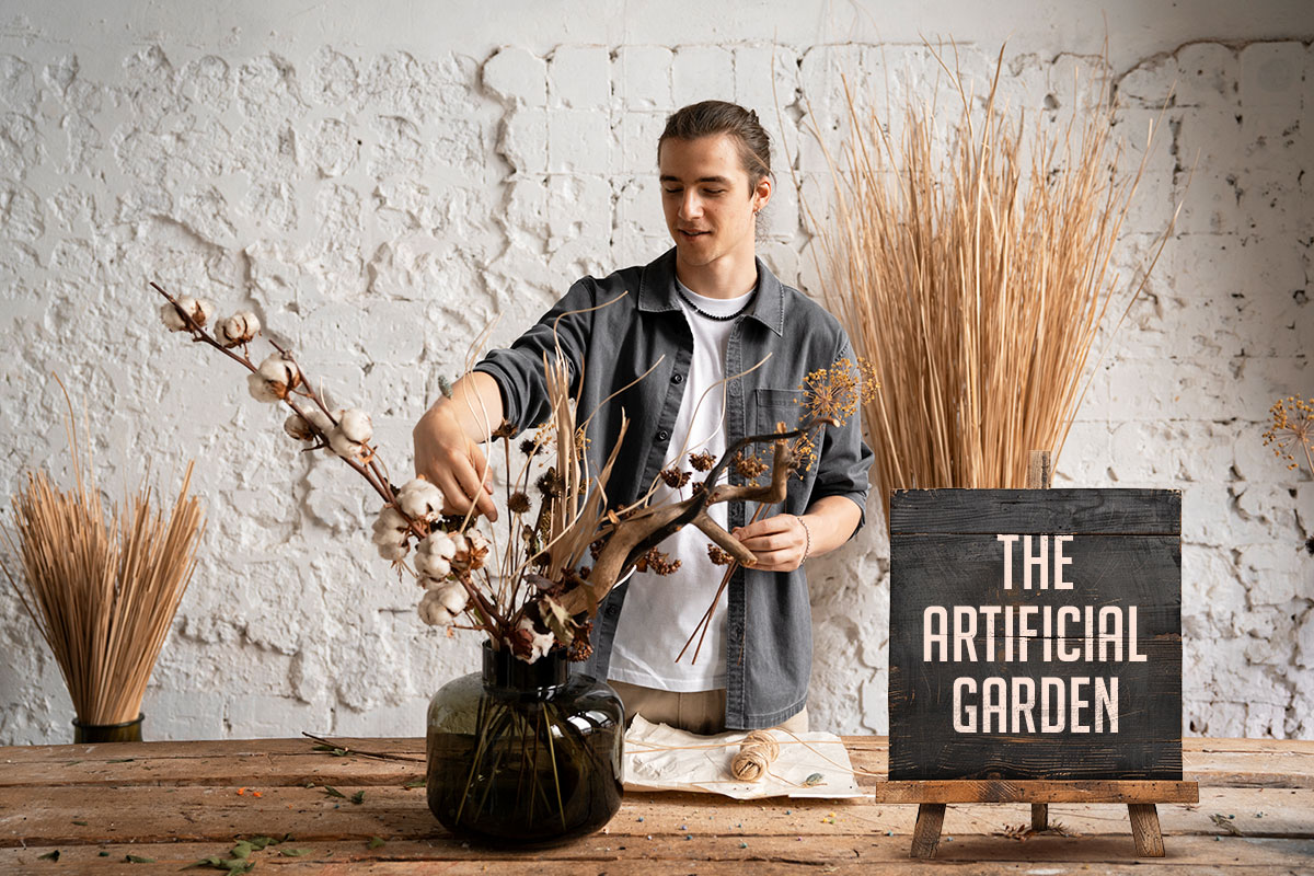 A flower shop owner arranging artificial plants next to a sign that says The Artificial Garden.
