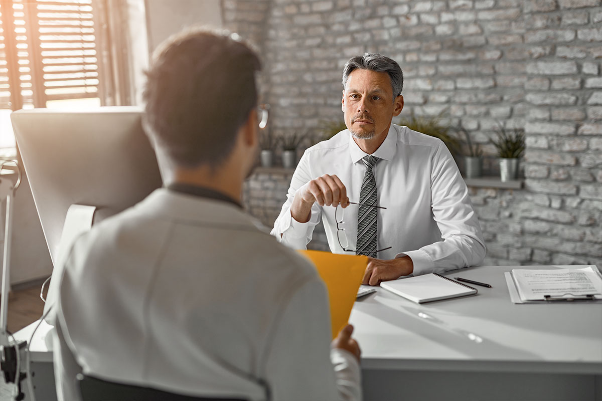 How to Hire Employees Like a 7-Figure Recruiter 8 Two businessmen sitting across from each other during a job interview.