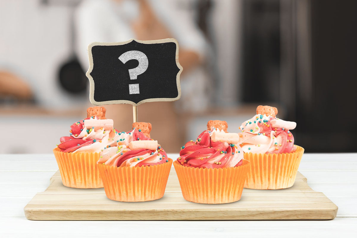 A small sign with a question mark sticking out of a cupcake.
