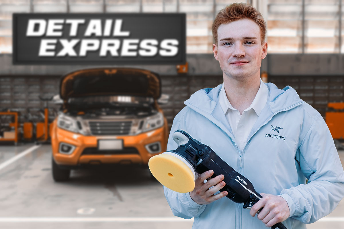 A car detailing business owner in an auto shop with a sign that says Detail Express.