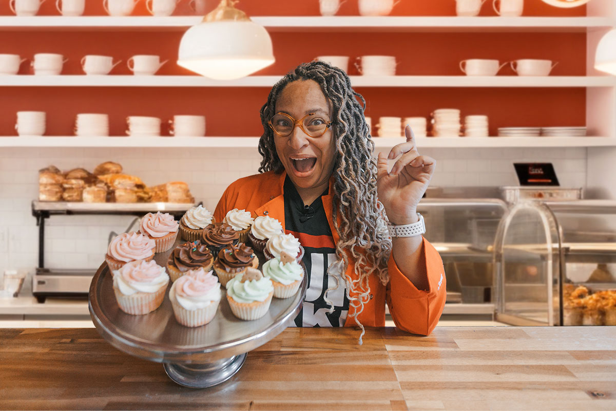 The owner of The Cupcake Collection posing with a tray of cupcakes.