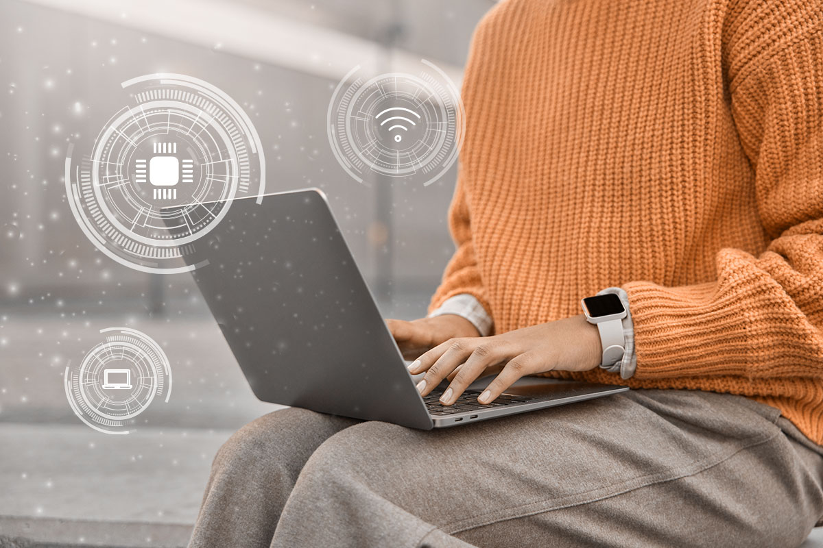 A business owner working on a laptop while automation-themed symbols float in the air nearby.