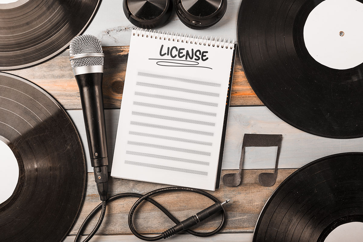 The word license on a notebook surrounded by a microphone and vinyl records.