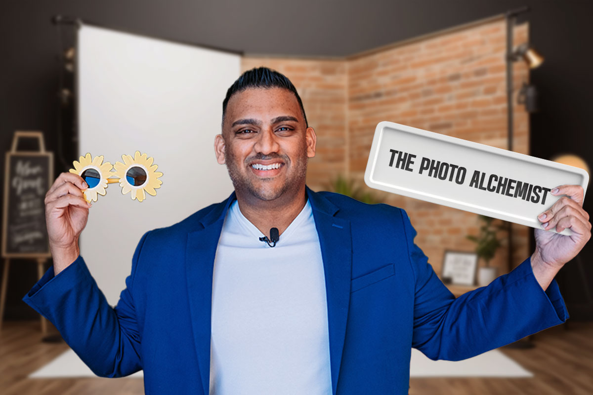 A photography business owner holding a prop in one hand and a sign that says The Photo Alchemist in the other.