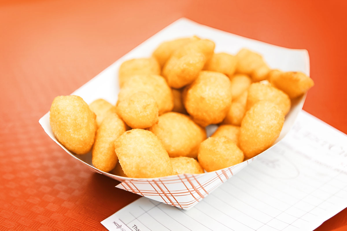 A to-go container of cheese curds sitting on top of a restaurant check.