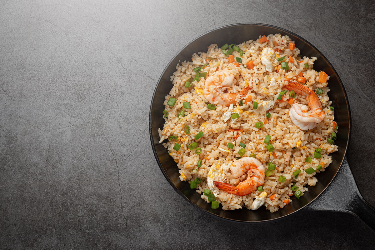 A cast iron skillet full of fried rice and shrimp.