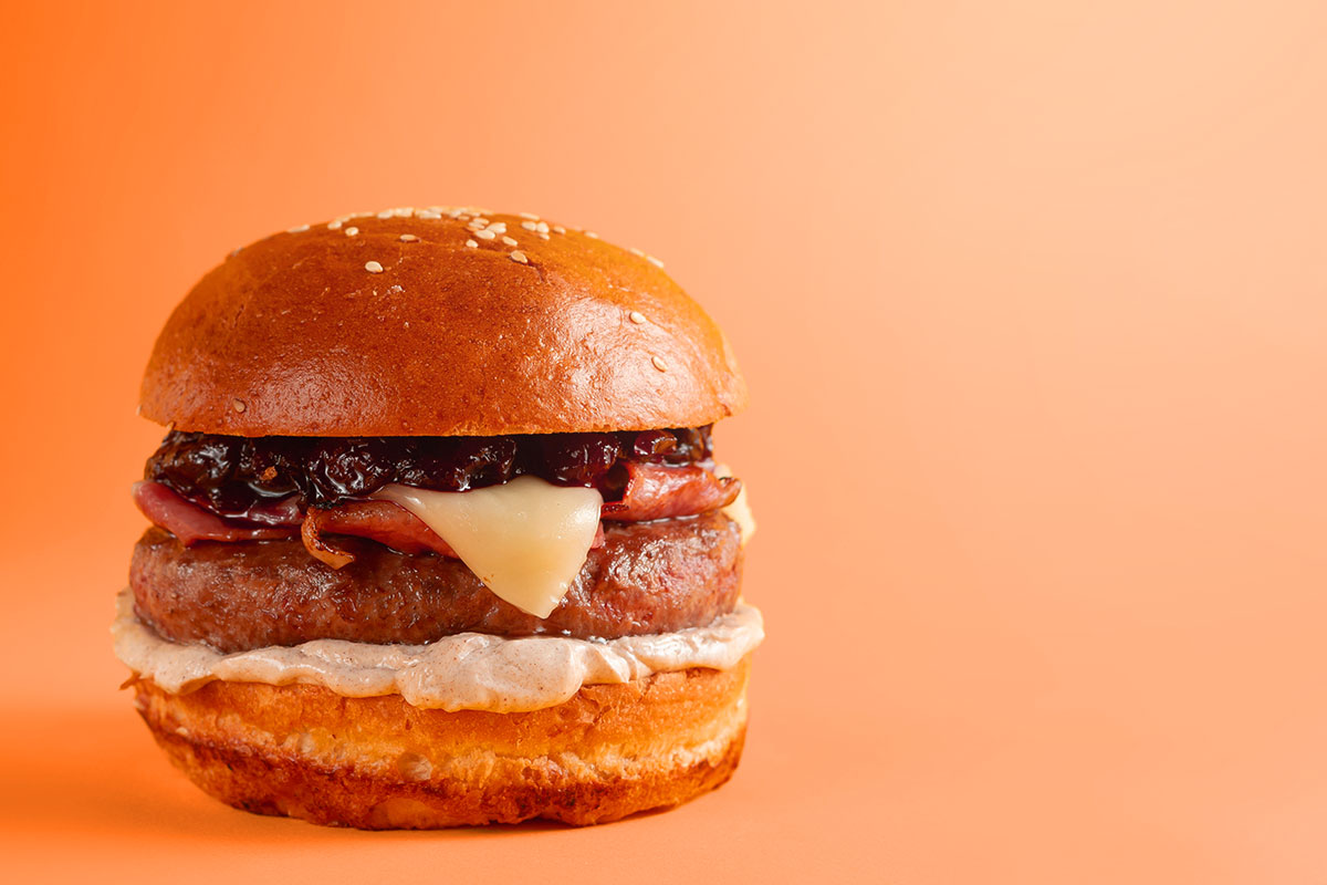 A fresh gourmet cheeseburger with sauces and toppings.
