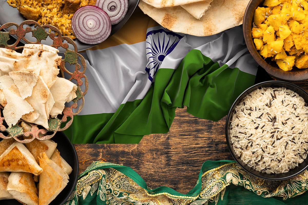 An Indian flag on a table surrounded by traditional Indian foods.