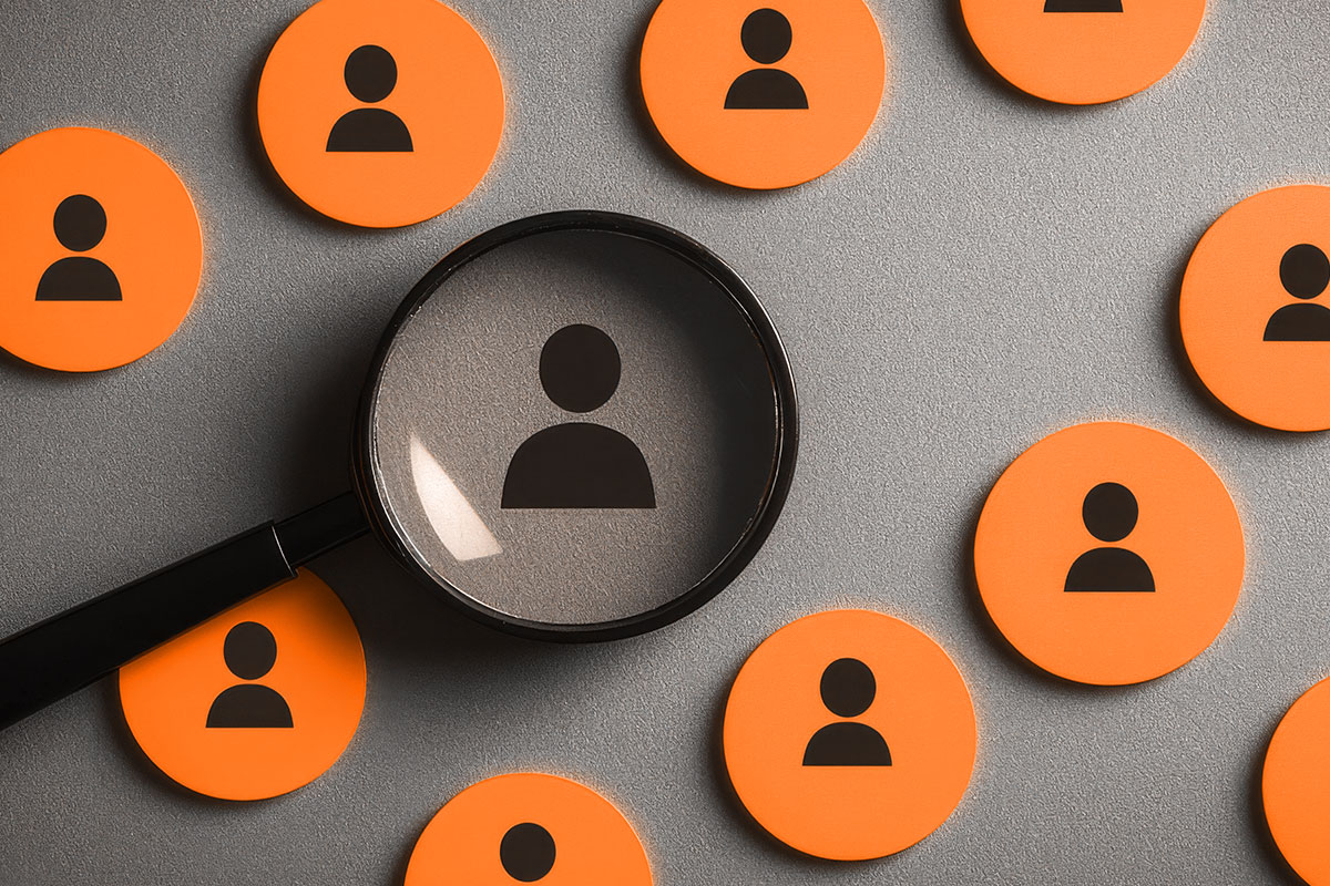 Small Business Marketing 12 A magnifying glass singling out one icon from a group of icons representing individual people.