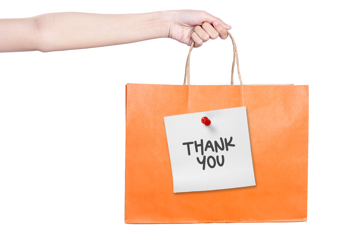 Business Thank You Messages to Customers 4 A gift bag with a note pinned to the side that says thank you.