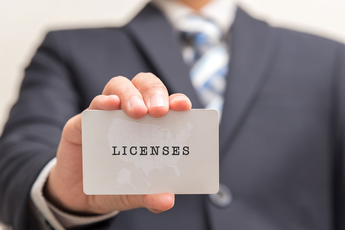A businessman holding up a card that says licenses.